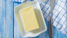 there is a plate with butter on it next to a knife and fork, along with a napkin