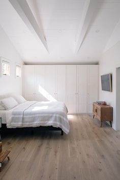 a bedroom with white walls and wooden floors