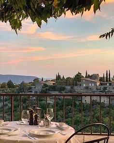 an outdoor dining area with table and chairs, overlooking the countryside at sunset or dawn