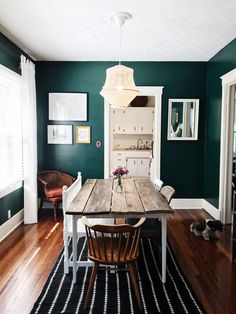 a dining room with green walls and wooden floors