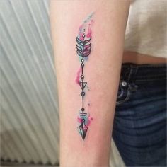 an arrow tattoo on the arm with pink watercolor paint splattered over it