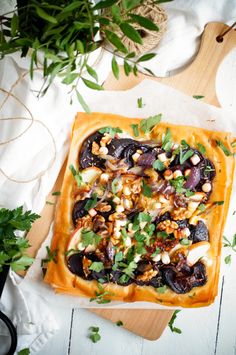 an overhead view of a square pizza on a cutting board with fresh herbs and other toppings