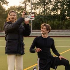 two people standing on a tennis court holding up signs