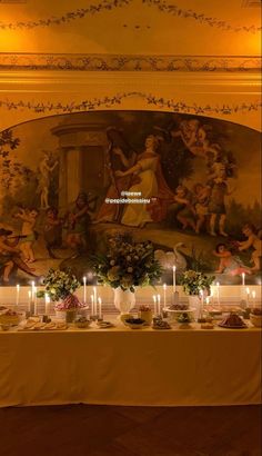 a table topped with lots of candles next to a painting on the side of a wall