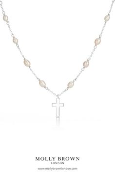 Designed using freshwater pearls the Cross on Pearl Station Necklace features a sterling silver cross set on the 16" freshwater pearl necklace adjusted at 14" to fit most ages. The cross measures 10mm in width 2mm in depth and a total drop of 15mm sitting delicately upon the pearls. This necklace would make a beautiful gift for a Baptism or Holy Communion. #holycommuniongift #holycommunionjewelry #holycommuniongiftgirls #girlsrosary #girlscross #childrensjewelry #mollybrownlondon # pearlcross Elegant Silver Cross Pearl Necklace, Silver Cross Pendant Necklace With Pearl Chain, Silver Cross Necklace With Pearl Chain, Silver Pearl Cross Pendant Necklace, Silver Pearl Necklace With Cross Pendant, Silver Cross Necklace With Pearl Chain For Gift, Silver Cross Pendant Pearl Necklace As Gift, Silver Cross Necklace With Pearl Chain As Gift, Silver Cross Necklace With Pearl Charm