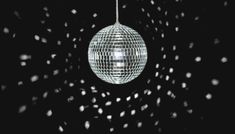 a disco ball hanging from the ceiling with confetti falling around it in front of a black background