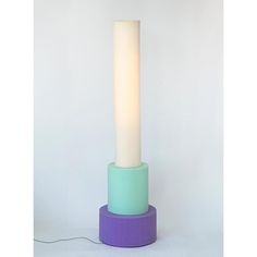 a lamp that is sitting on top of a purple and green stand with a white light