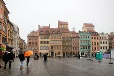 several people walking down a cobblestone street with umbrellas in the rain,