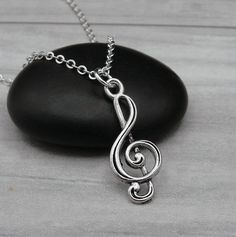 a silver treble necklace on a black rock