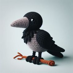 a crocheted black and white bird with orange feet