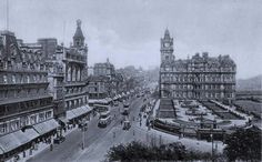 an old black and white photo of a city street with tall buildings on both sides