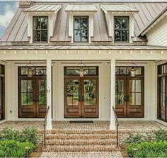 a white house with brown front doors and steps leading up to the front door is shown in an instagram