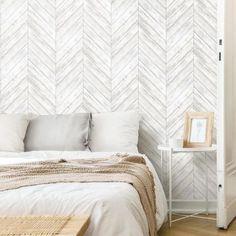 a white bed sitting next to a wooden table on top of a hard wood floor