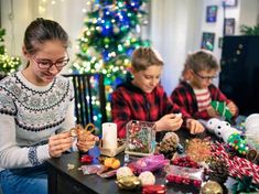 two children and an adult sitting at a table with christmas decorations