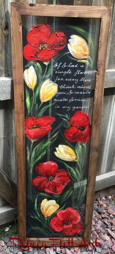 a painting with red and yellow flowers painted on the side of a wooden frame in front of a fence