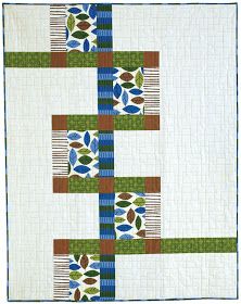 a white quilt with blue, green and red designs on the border is displayed in front of a white background