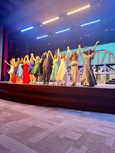 a group of people standing on top of a stage with their arms in the air