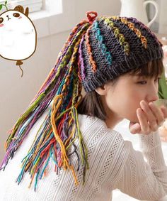 a woman wearing a multicolored knitted hat with dreadlocks on her head