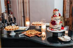 a table topped with cakes and desserts next to candles