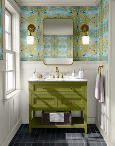 a bathroom with green vanity and blue tile flooring in front of a wallpapered wall