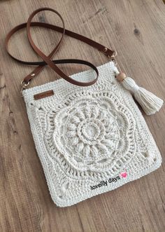 a white crocheted bag with a tassell on the front and handle