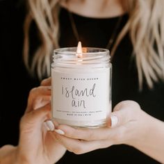 a woman holding a candle that says island ann on it in front of her face