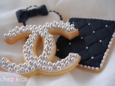 two decorated cookies are sitting on a white cloth with black and white trimmings