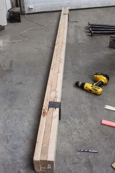 tools are laying on the floor next to a piece of wood