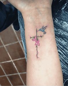 a cross with two birds on it and pink flowers in the middle of its arm