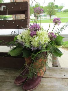 purple and white flowers are in an old boot