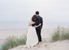 a bride and groom embracing on the beach