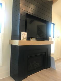 an empty room with a black fireplace and wood paneling on the wall above it