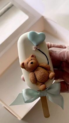 a hand holding a cake shaped like a teddy bear on top of a toothbrush