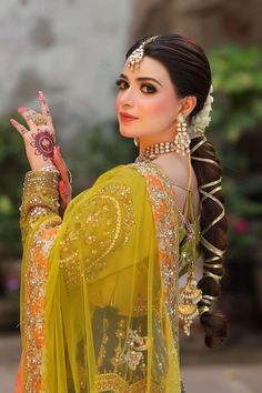 a woman in an orange and yellow outfit holding her hand up to the side with one hand