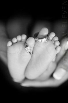 a black and white photo of a baby's feet with a ring on it