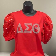 a red shirt with the word delta on it is sitting on a mannequin