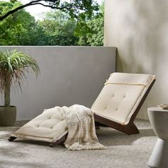 a white chair sitting on top of a floor next to a potted palm tree