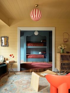 a room with bunk beds and other furniture in the corner, along with an orange chair