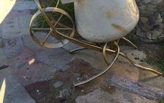 an old fashioned milk jug sitting on a metal stand in front of a stone wall