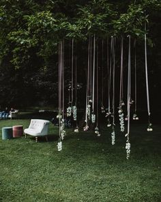 an outdoor area with chairs and flowers hanging from the trees, in front of a lawn