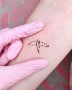 a small bird tattoo on the left inner arm