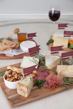 a table topped with cheese and crackers next to a glass of wine