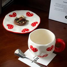 a cup and saucer sitting on top of a wooden table next to a spoon