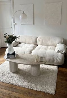 a white couch sitting on top of a wooden floor next to a table and lamp