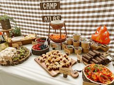 a table topped with lots of food next to a sign that says camp atlast