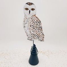 an owl figurine sitting on top of a small black stand with white speckles