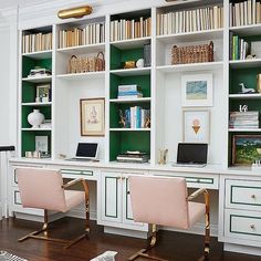 two pink chairs sitting in front of a white desk with bookshelves and shelves