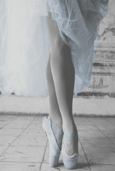 black and white photograph of a woman's feet in ballet shoes with tulle skirt