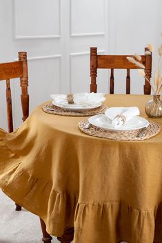 the table is set for two with plates and napkins on it, along with wheat stalks