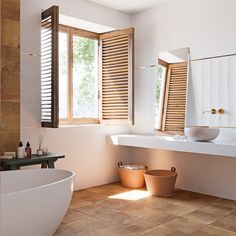 a bath room with a tub a sink and two windows on the wall next to each other